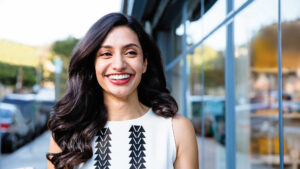 Woman smiling confidently while representing discreet Invisalign clear aligner treatment