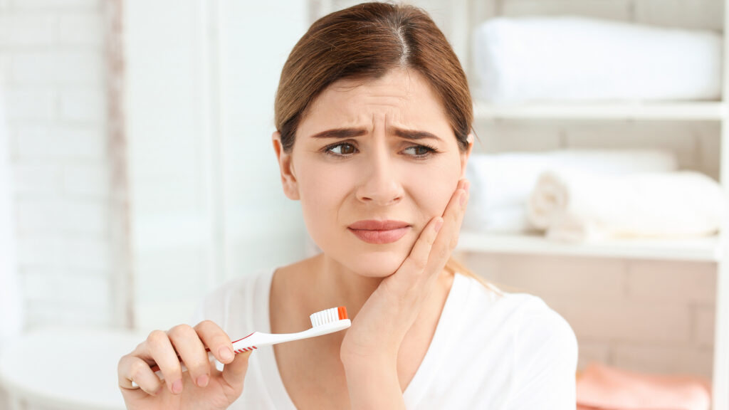 Young woman experiencing tooth or jaw pain that may require evaluation by a dentist
