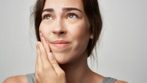 Woman experiencing jaw discomfort representing symptoms and duration of a TMJ disorder