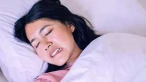 Woman sleeping while experiencing bruxism, nighttime teeth grinding and jaw tension