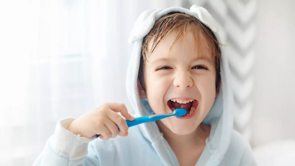 Young boy smiling with a toothbrush while practicing good daily oral hygiene