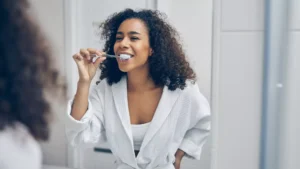 Woman brushing her teeth at home as part of a daily preventive dental care routine