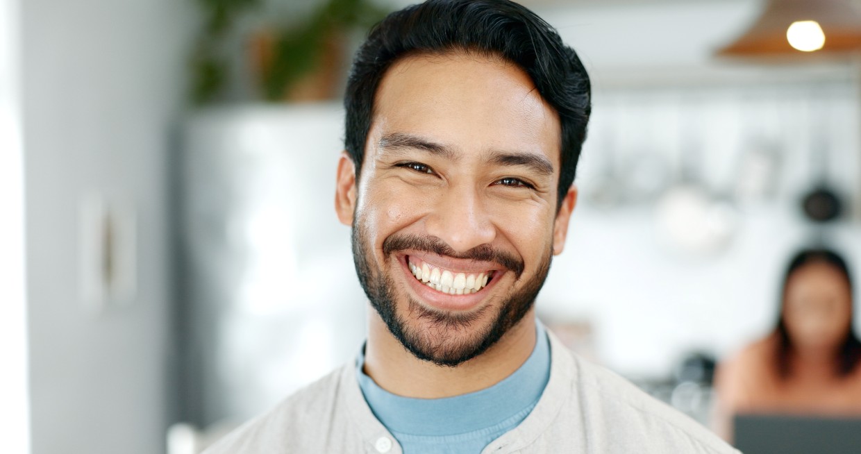 Man smiling confidently at home after maintaining a healthy smile